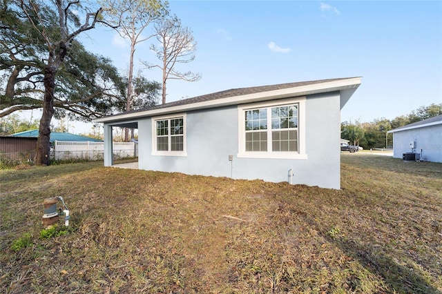 rear view of property featuring a yard and central air condition unit