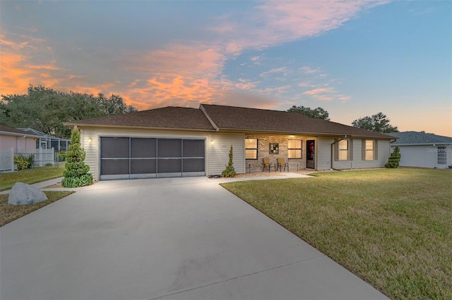 ranch-style house with a garage and a lawn