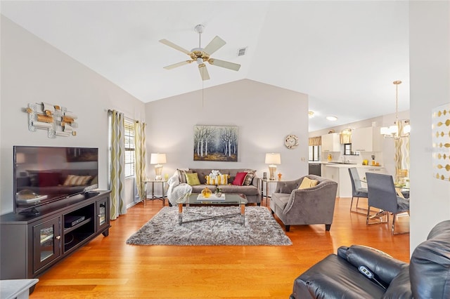 living room featuring lofted ceiling, sink, ceiling fan with notable chandelier, and light wood-type flooring