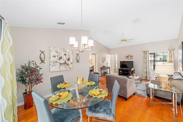 dining area featuring ceiling fan with notable chandelier, wood-type flooring, and vaulted ceiling