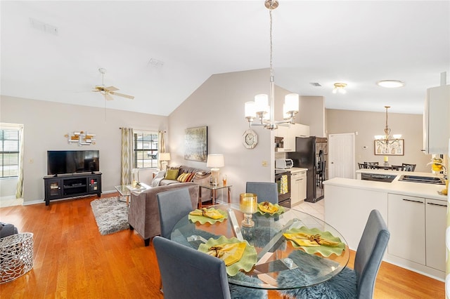 dining space with vaulted ceiling, ceiling fan with notable chandelier, light hardwood / wood-style floors, and sink