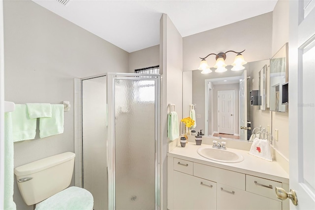 bathroom featuring a shower with door, vanity, and toilet