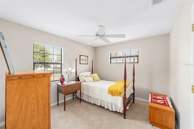 bedroom with multiple windows, ceiling fan, and light carpet