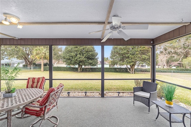 sunroom / solarium with beam ceiling, a healthy amount of sunlight, and ceiling fan