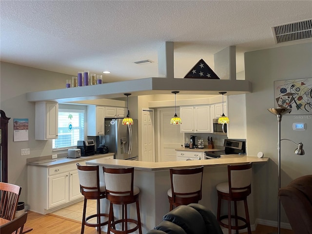 kitchen with white cabinetry, a breakfast bar, kitchen peninsula, and appliances with stainless steel finishes