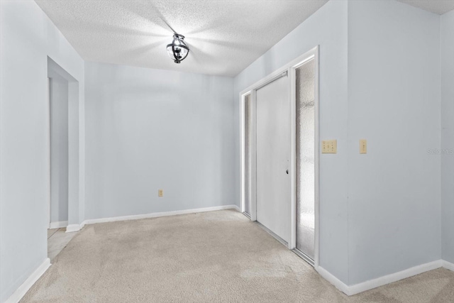 spare room featuring light carpet and a textured ceiling