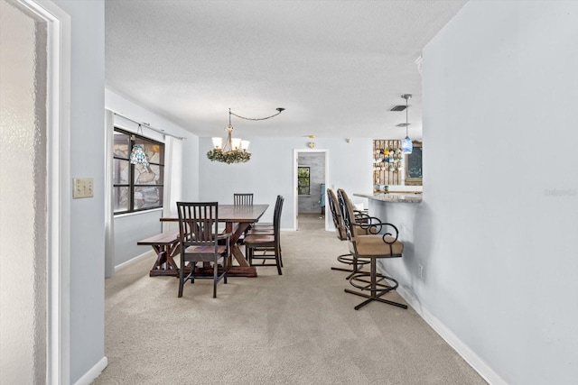 carpeted dining room with a notable chandelier and a textured ceiling