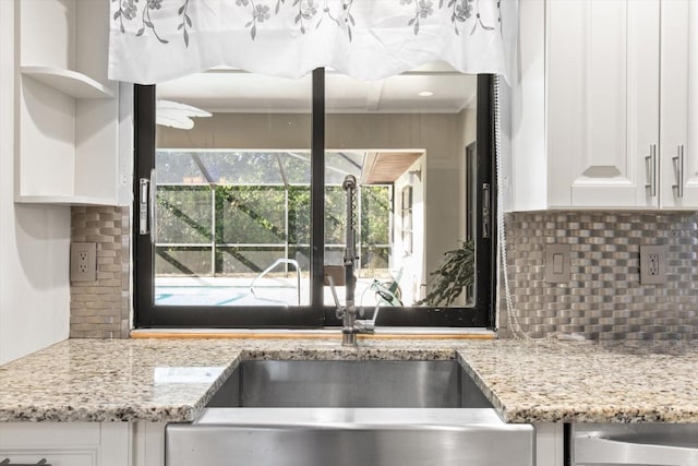 kitchen featuring white cabinetry, light stone countertops, sink, and tasteful backsplash