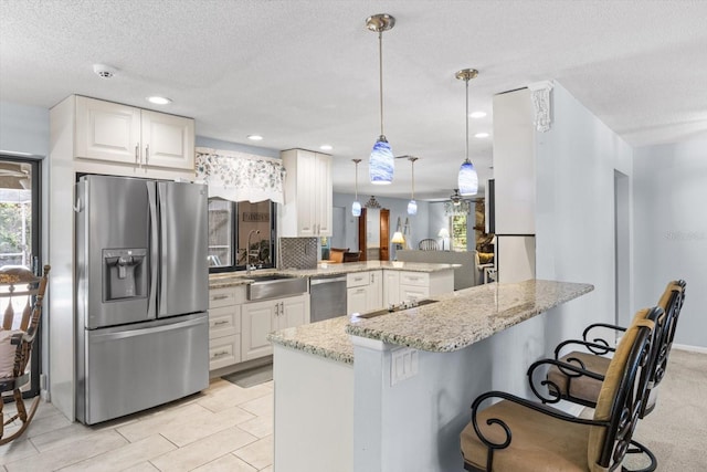 kitchen with sink, white cabinetry, hanging light fixtures, appliances with stainless steel finishes, and kitchen peninsula