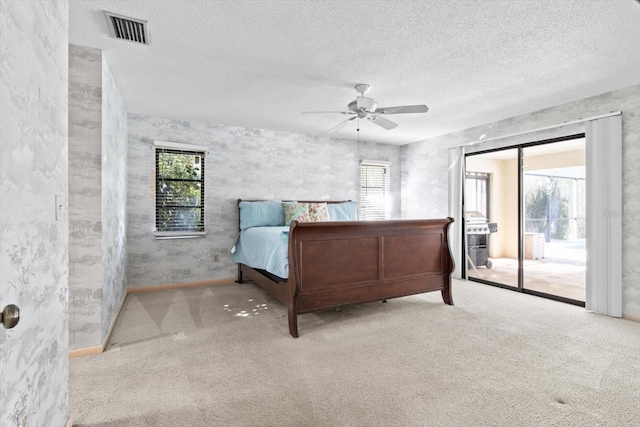 bedroom with a textured ceiling, access to outside, light colored carpet, and ceiling fan