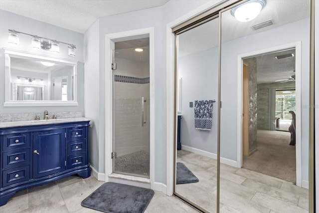 bathroom featuring vanity, an enclosed shower, and a textured ceiling