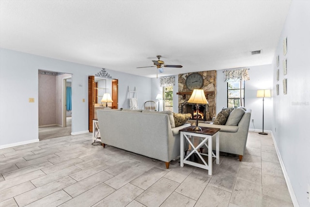 living room with a stone fireplace and ceiling fan