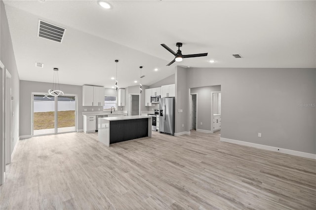 kitchen with decorative light fixtures, stainless steel appliances, white cabinets, and a kitchen island