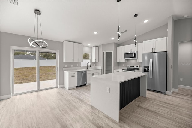 kitchen with sink, appliances with stainless steel finishes, white cabinetry, hanging light fixtures, and a center island