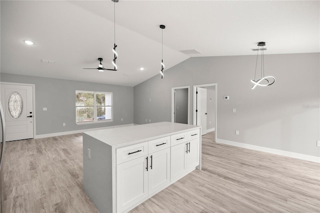 kitchen featuring white cabinetry, hanging light fixtures, vaulted ceiling, and light wood-type flooring