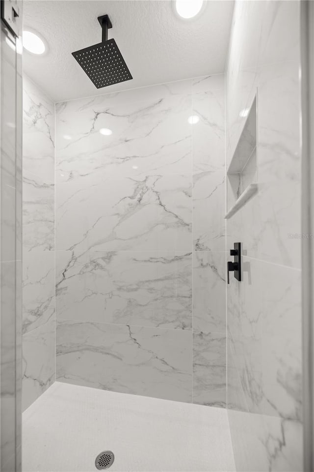 bathroom featuring a tile shower and a textured ceiling