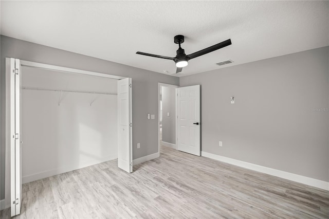 unfurnished bedroom featuring light wood-type flooring, a textured ceiling, ceiling fan, and a closet