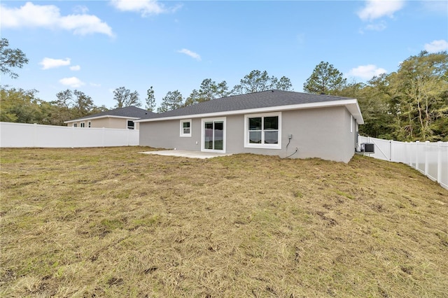 rear view of house with central AC, a patio, and a lawn