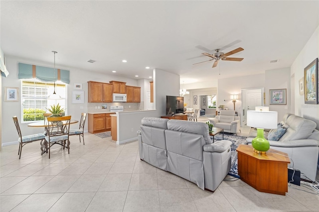 living room featuring light tile patterned floors and ceiling fan with notable chandelier