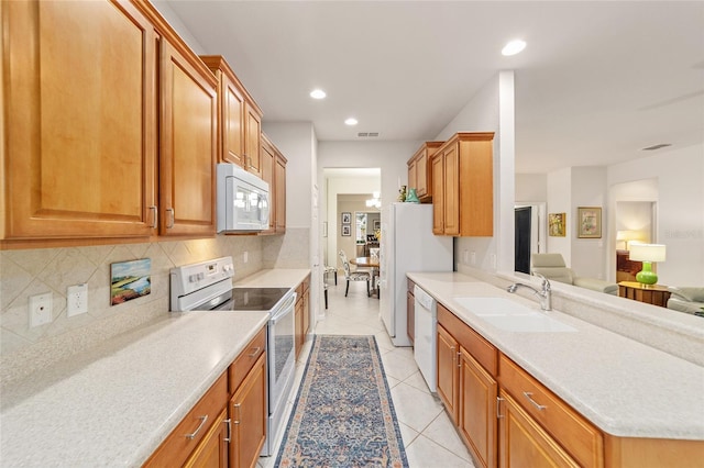 kitchen featuring sink, light tile patterned floors, backsplash, and white appliances