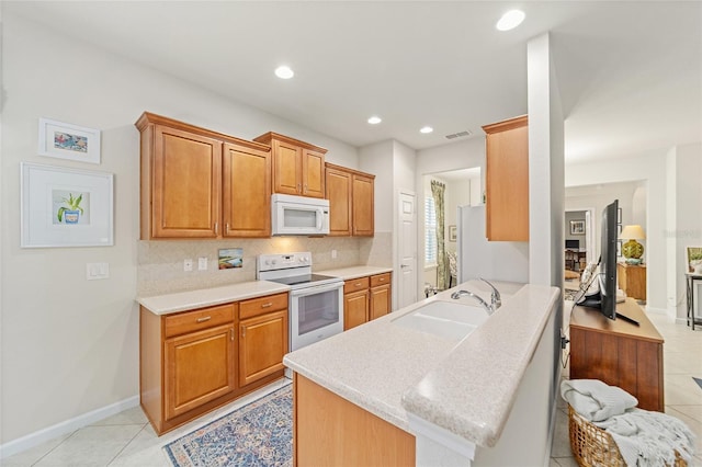 kitchen featuring tasteful backsplash, sink, light tile patterned floors, kitchen peninsula, and white appliances