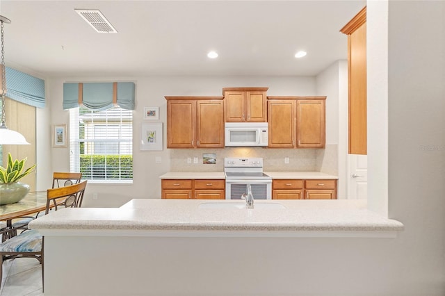 kitchen with light tile patterned flooring, kitchen peninsula, pendant lighting, white appliances, and backsplash