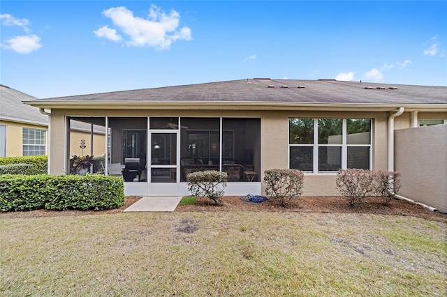 rear view of house featuring a yard and a sunroom