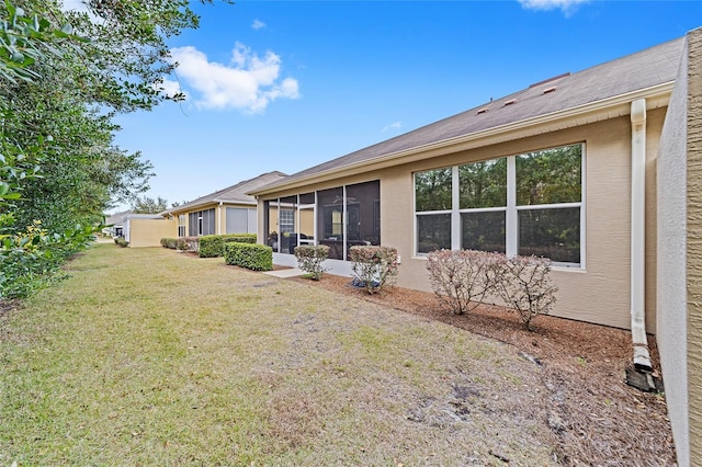 back of house featuring a sunroom and a lawn