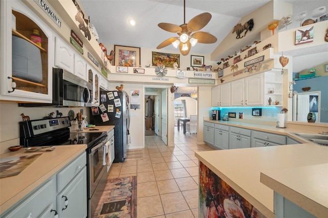 kitchen with appliances with stainless steel finishes, sink, white cabinets, light tile patterned floors, and ceiling fan