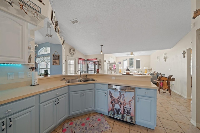 kitchen with light tile patterned flooring, pendant lighting, sink, stainless steel dishwasher, and kitchen peninsula