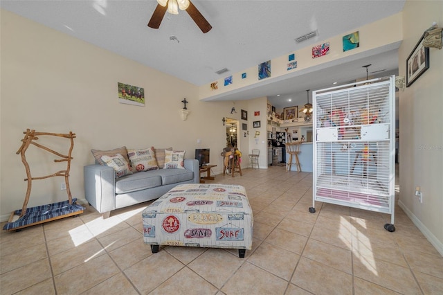 living room with ceiling fan, a textured ceiling, and light tile patterned floors