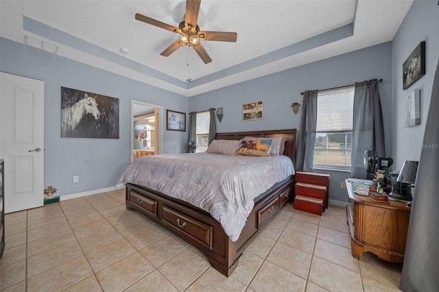 tiled bedroom featuring connected bathroom, ceiling fan, a raised ceiling, and a textured ceiling