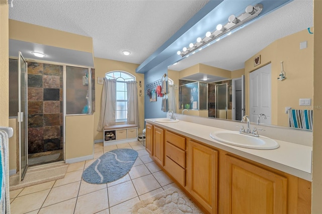 bathroom with vanity, a shower with shower door, tile patterned flooring, and a textured ceiling