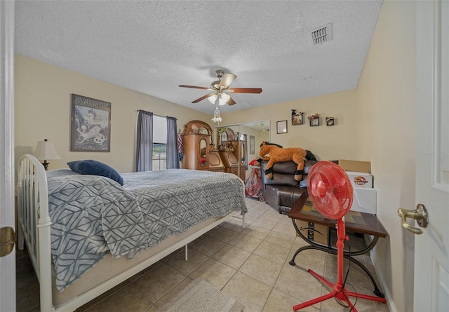 bedroom with light tile patterned flooring, ceiling fan, and a textured ceiling