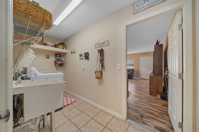 laundry room featuring washer / clothes dryer, sink, light tile patterned floors, and a textured ceiling