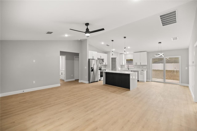 kitchen with hanging light fixtures, stainless steel appliances, white cabinets, and a kitchen island