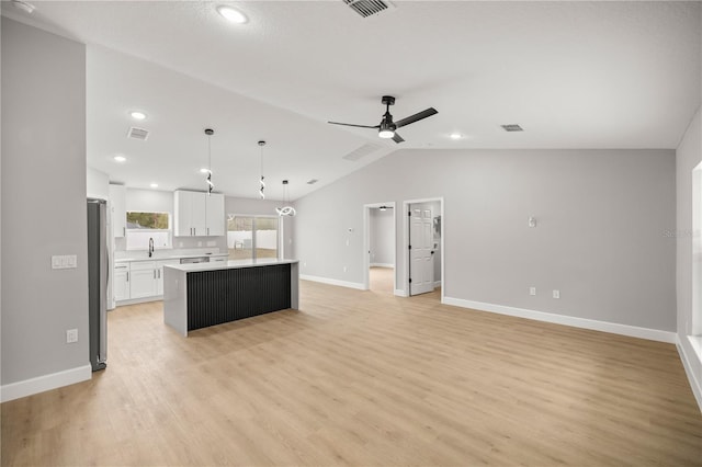 kitchen with a center island, hanging light fixtures, stainless steel fridge, light hardwood / wood-style floors, and white cabinets