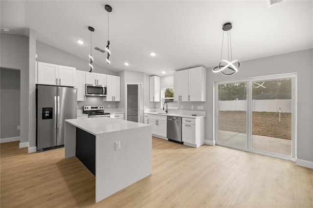 kitchen with a kitchen island, white cabinets, hanging light fixtures, light hardwood / wood-style floors, and stainless steel appliances