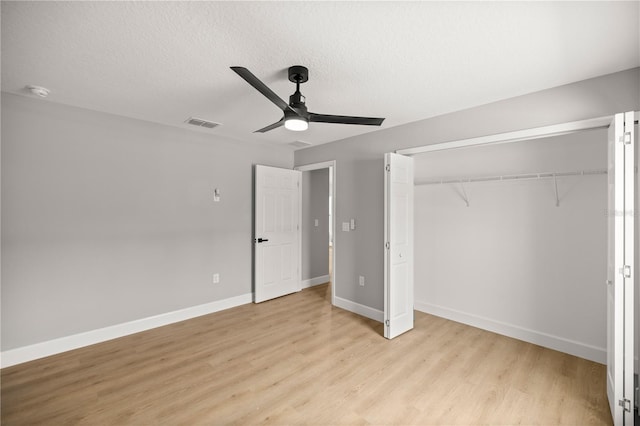 unfurnished bedroom featuring ceiling fan, a textured ceiling, a closet, and light wood-type flooring