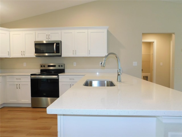14268 SE 27th Ct, Summerfield, FL 34491 - kitchen with appliances with stainless steel finishes, vaulted ceiling, white cabinets, light wood-style floors, and light stone countertops