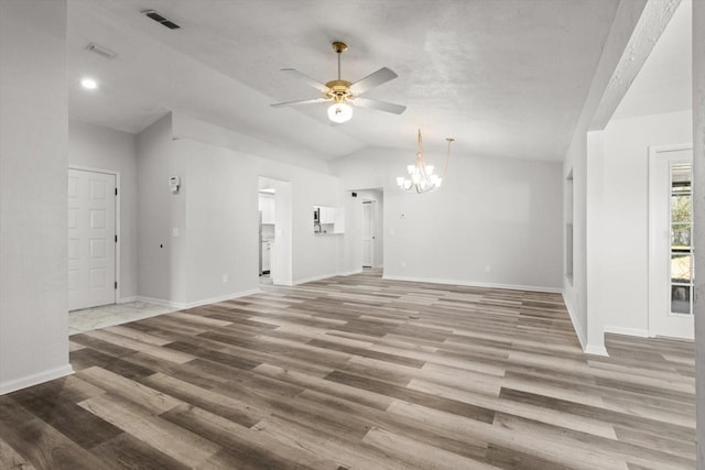 unfurnished living room featuring hardwood / wood-style floors, lofted ceiling, and ceiling fan with notable chandelier