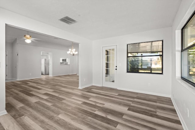 unfurnished room featuring ceiling fan with notable chandelier and hardwood / wood-style floors