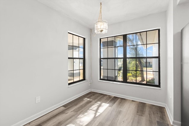 unfurnished room with an inviting chandelier and hardwood / wood-style flooring