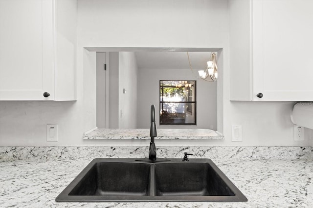 kitchen featuring sink, white cabinets, and light stone counters