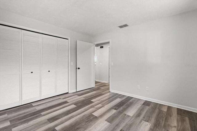 unfurnished bedroom featuring wood-type flooring and a closet