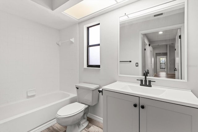 full bathroom featuring vanity, wood-type flooring, washtub / shower combination, and toilet