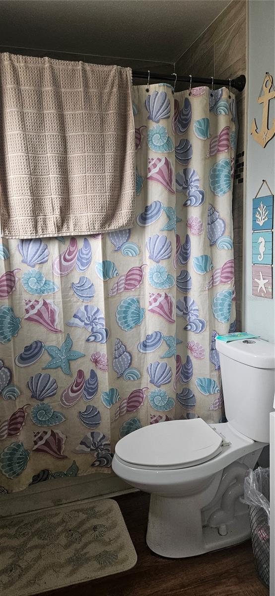 bathroom with hardwood / wood-style flooring, curtained shower, and toilet