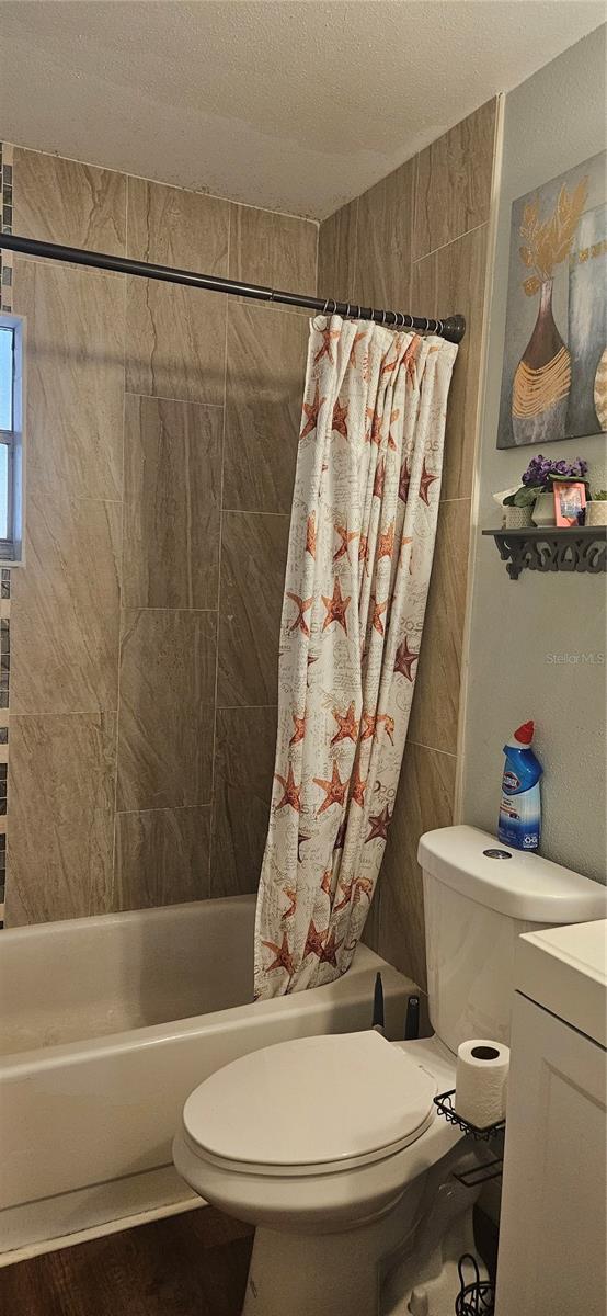 full bathroom with shower / bath combination with curtain, vanity, and toilet