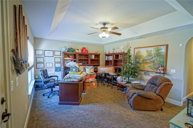 carpeted home office featuring a tray ceiling, a textured ceiling, and ceiling fan