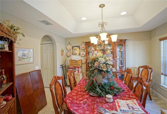 dining space featuring a chandelier, plenty of natural light, and a raised ceiling